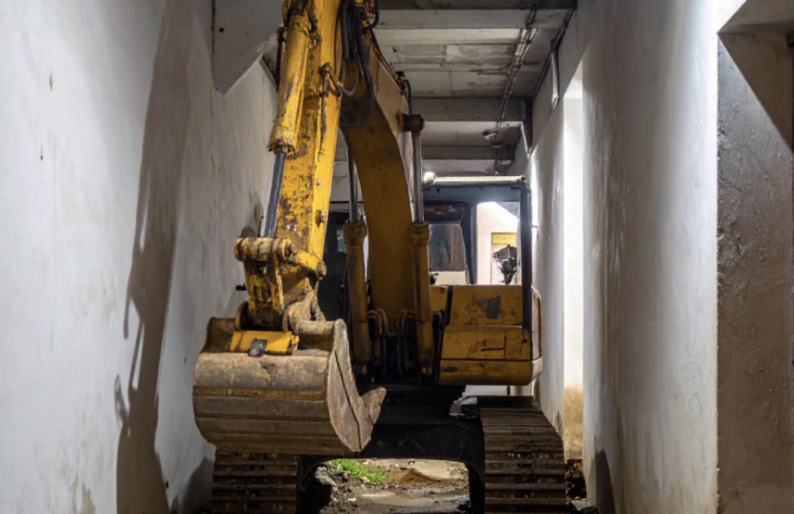 Mini excavator working inside a narrow indoor corridor