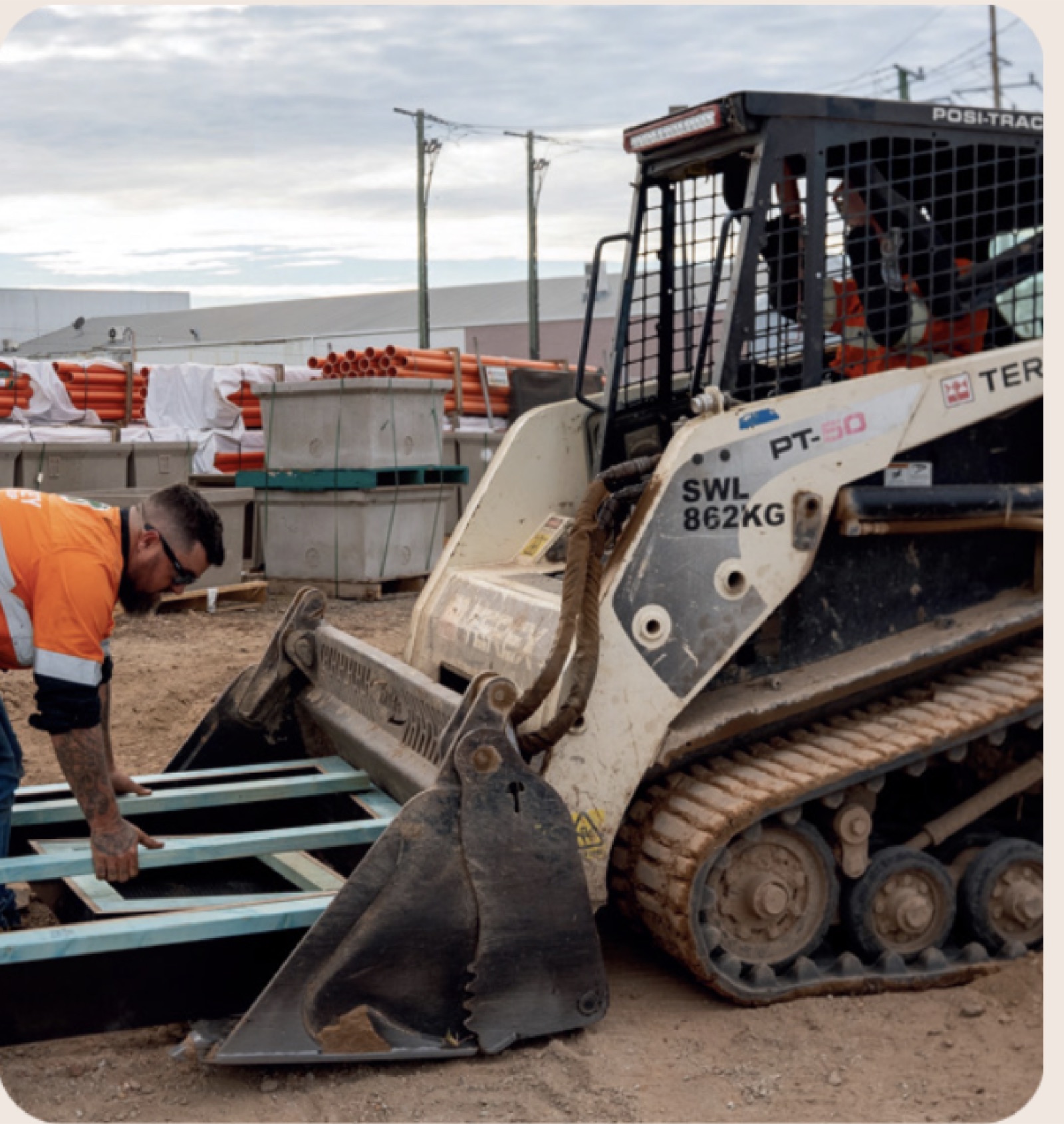 Positrack loader on site with drainage pipes stacked nearby